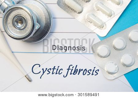 Diagnosis Cystic Fibrosis. Doctors Stethoscope, Electronic Thermometer And Two Blisters Of Pills Lyi