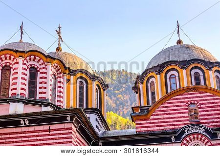 Rila Monastery, Bulgaria Church Domes And Cross Close-up And Autumn Mountain Trees At Background