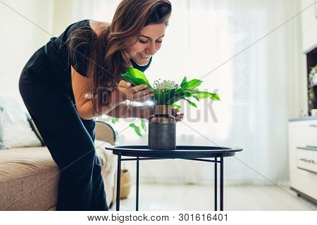 Woman Smelling Flowers In Vase On Table. Allergy Free. Housewife Taking Care Of Coziness In Apartmen