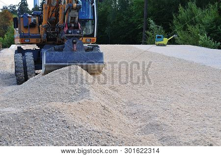 Digger And Vibrating Machine At Construction Site With Limestone Gravel To Be Nivellated