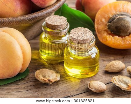 Apricot kernel oil and apricot kernels on wooden background.