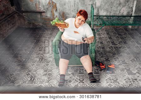 Overweight woman watches TV, bulimic, fatty