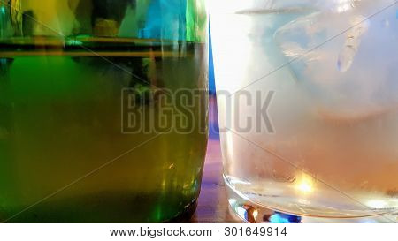 Close Up Of An Ice Cold Green Bottle Of Drink Next To A Frosted Ice Cold Glass