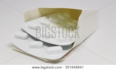 2 Strips Of Sealed Tablets Sticking Out Of A Box.