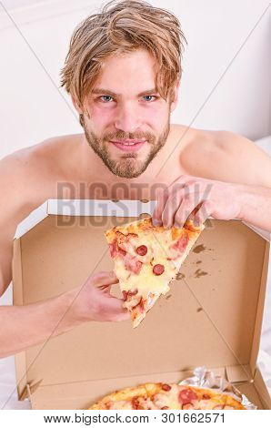Sexy Man Eat Pizza Lying On Bed. Shirtless Handsome Young Man With Pizza On Bed. Hungry Young Man In