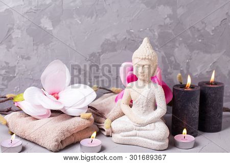 Black Burning Candles , Towels,  Decorative Buddha And Pink Magnolia Flowers On Grey Textured Backgr
