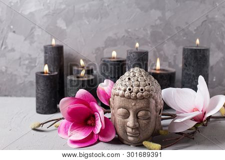 Black Burning Candles , Buddha And Pink Magnolia Flowers On Grey Textured Background. Spa Or Still L