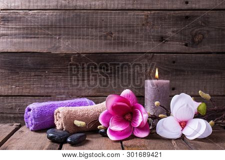 Set Of Towels For Spa, Burning Candle, Black Stones And Pink  Magnolia Flowers On  Rustic Textured W