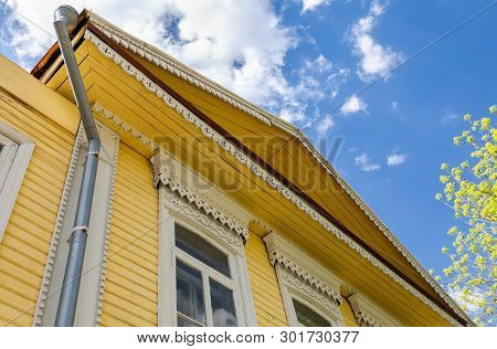 Russian Traditional Wooden Architecture. Facade Of An Old House Decorated With Wooden Carvings, Plat