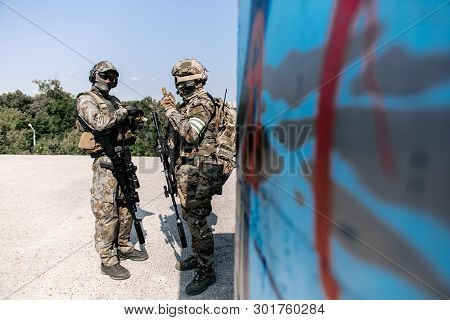 Two Armed Soldiers In An Open-air Shelter