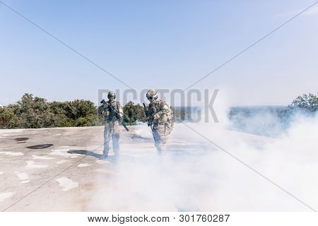 Army Soldiers During Military Operation Standing With Sniper Rifles In Smoke. Concept Of War, Army A