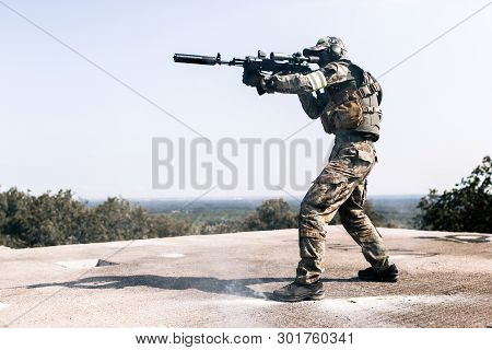 Armed Man In Camouflage With Sniper Gun In Hand Standing On The Roof