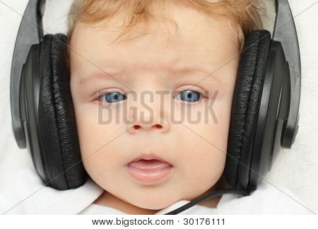 Happy baby boy 3 month old in earphones babbling