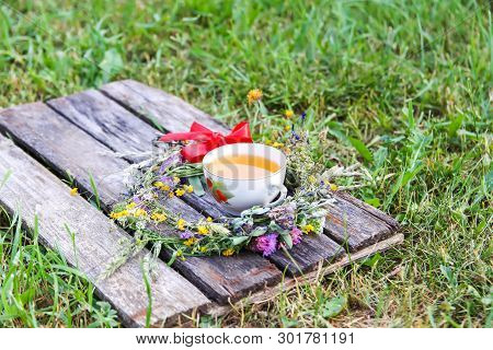 Herbal Tea Of Medical Plants In A Cup On Weathered Wooden Boards Outdoors.