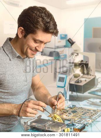 Young Energetic Male Tech Or Engineer Repairs Electronic Equipment In Research Facility. Shallow Dof