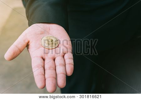 Golden Bitcoin In A Man Hand, Digitall Symbol Of A New Virtual Currency.