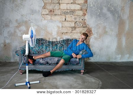 Man Lies On The Couch Resting. Fan. Air Conditioning.
