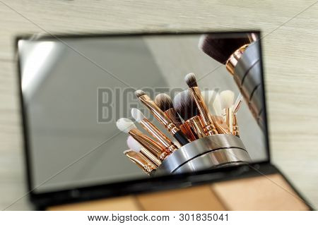 Makeup Brushes Are Reflected In A Palette Mirror With Shadows