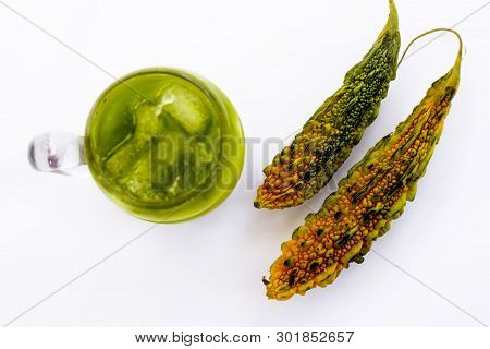 Raw Organic Bitter Melon Or Bitter Gourd With Its Extracted Juice In A Transparent Glass With Some I