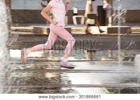 Girl Teenager Happily Rushes Between Spray Of A Fountain In A Summer Sunny Day