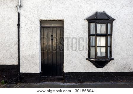 Exterior View Of A Beautiful Old English Stone Cottage With Door And Window.