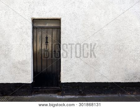 Exterior View Of A Beautiful Old English Stone Cottage With Door.