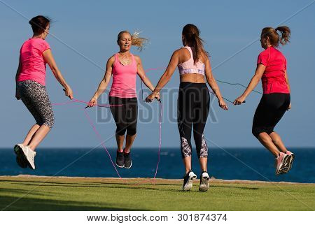 Group Of Young People Doing Their Fitness Training By The Sea, Using Skipping Rope