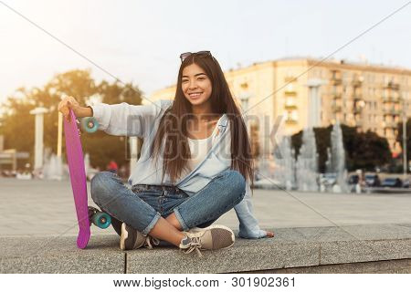 Cool Asial Teenage Girl Sitting With Skateboard, Popular Teen Sport, Summer Evening