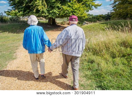 Elderly Couple Holding Hands While Visiting The British Countryside.