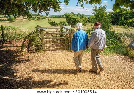 Elderly Couple Hold Hands,walking In The British Countryside.