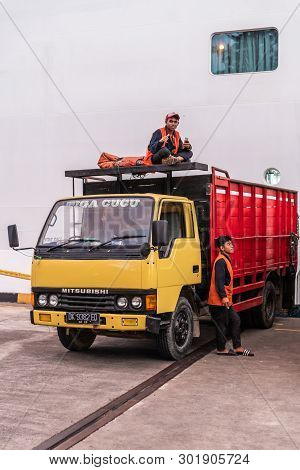 Bali, Indonesia - February 25, 2019: Closeup Of Two Young Man Waiting At Of Their Parked Truck. One 