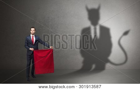 Businessman standing with red cloth in his hand and devil shadow on the background