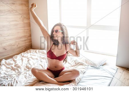 Seductive Young Naked Dark-haired Woman On Bed In Morning. Well-built Sexy Woman Stratching Hand Up 