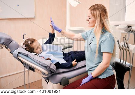 Adorable Little Girl And Pediatric Dentist Giving High Five Or Slapping Hands After Dental Procedure