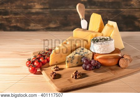 Composition Different Types Of Cheese With Walnuts And Grapes On Rustic Wooden Background. Blue Chee