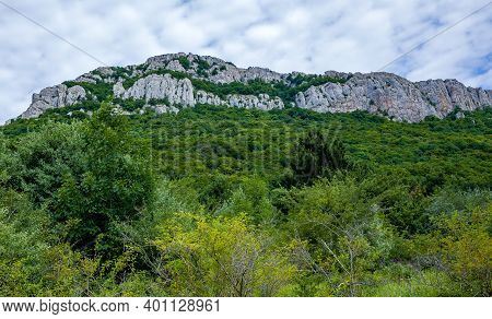 Inaccessible Rocks Surrounded By Green Forests And Shrubs In Hot Summers In Clear Sunny Weather.