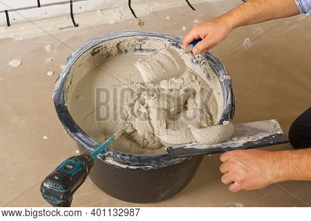 The Master Mixes The Plaster In A Bucket. Flat House Renovation, Master Mixed The Mortar In A Plasti
