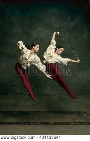 Flying. Two Young Female Ballet Dancers Like Duelists With Swords On Dark Green Background. Caucasia