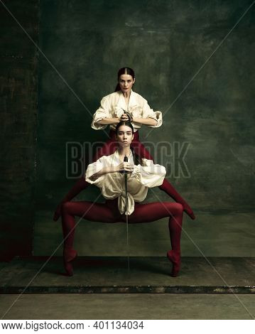 Bright. Two Young Female Ballet Dancers Like Duelists With Swords On Dark Green Background. Caucasia