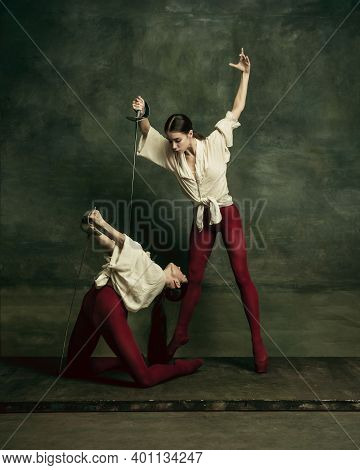 Motion. Two Young Female Ballet Dancers Like Duelists With Swords On Dark Green Background. Caucasia