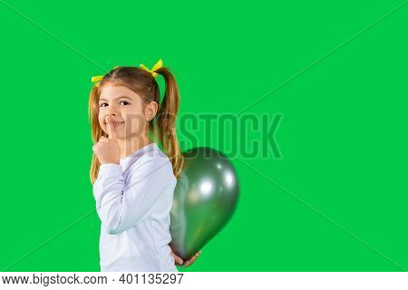 Preschool Girl Hides A Ultimate Grey Color Balloon Showing Quietly Tsss To The Camera. Green Backgro
