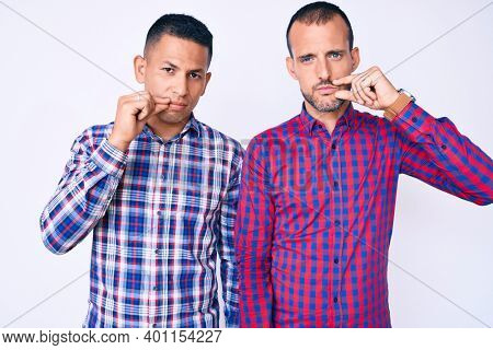Young gay couple of two men wearing casual clothes mouth and lips shut as zip with fingers. secret and silent, taboo talking 