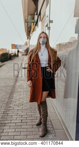 young ukrainian blonde woman in protective medical mask kn95 respirator on street against background