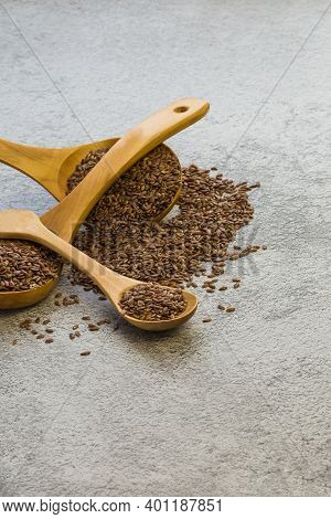 Flax Seeds In Three Wooden Spoons On A Concrete Background, A Dietary Product That Reduces Cholester