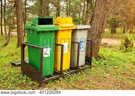Trash Bin Located In The Public Park. Three Containers Of Different Colors For Collecting Different 