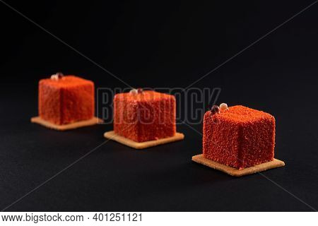 Closeup View Of Matte Orange Dessert Decorated With Chocolate Balls Isolated On Black Studio Backgro