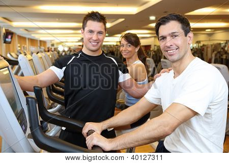 drei Freunde auf Heimtrainer in einer Turnhalle