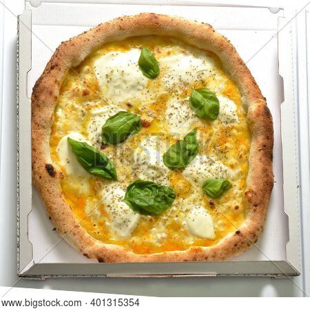 Just baked Mozzarella pizza Napoletan stile with yellow tomato and basil on pizza box ready to delivery