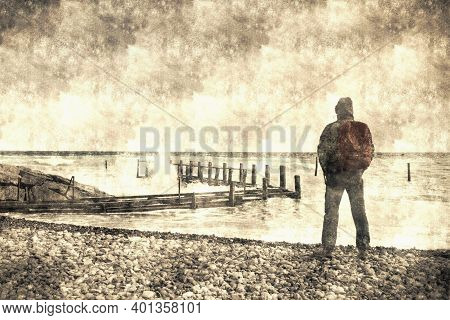 Young Man With Backpack Standing On Beach And Looking To Horizon Of Ocean. Concept For Adventure And
