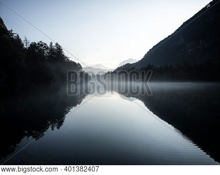 Low Clouds Fog Misty Mood Reflection Of Tree Forest In Lake Bluntausee Golling Salzburg In Austria A